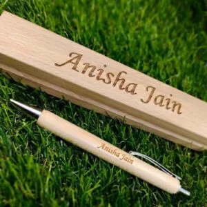 Wooden ball pen engraved with a name lying on grass beside a wooden box