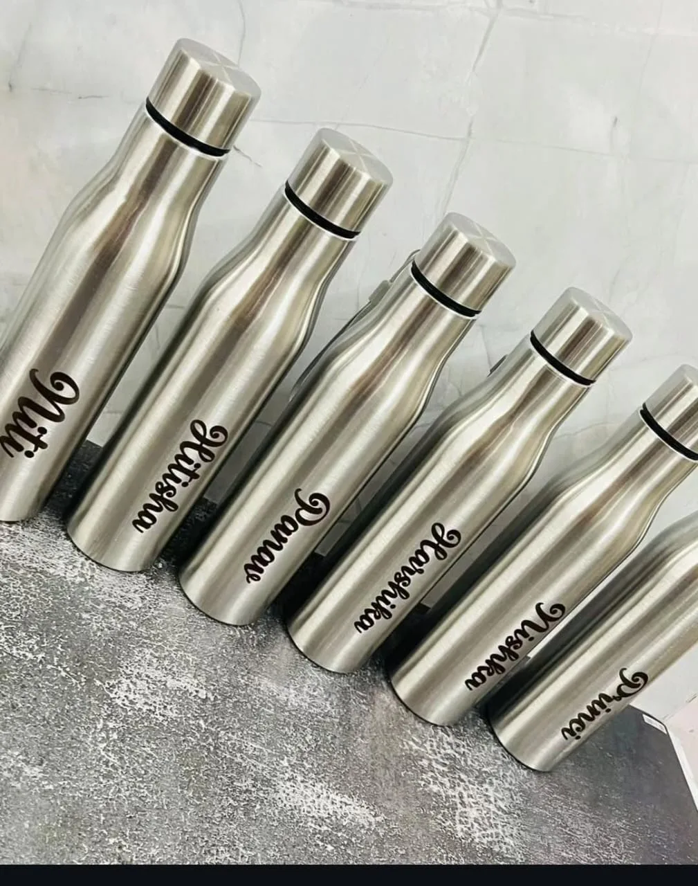 Row of classic curved steel water bottles engraved with different names