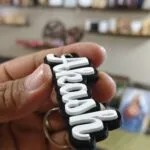 Black and white acrylic cut name keychain held in hand