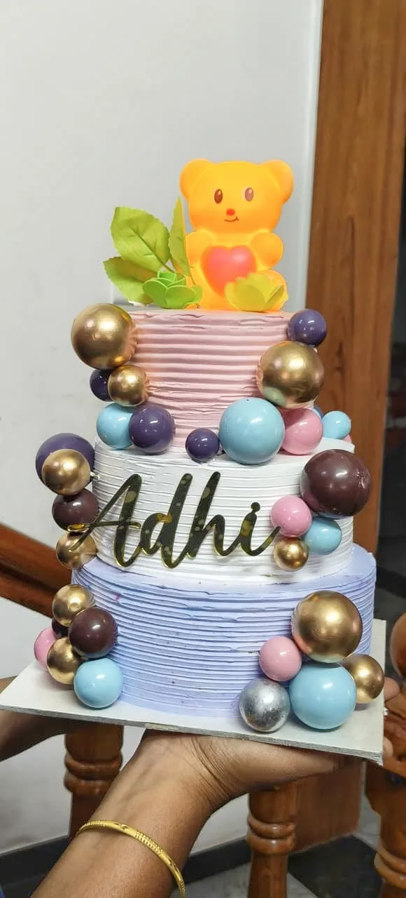 Cake with a gold acrylic name topper reading Adhi