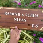 Wooden name plate with gold border reading Ramesh and Subha Nivas E-5