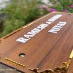 Angled view of a wooden name board with raised white lettering