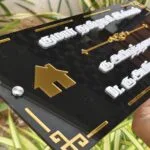Close view of raised white Tamil lettering on a black name board
