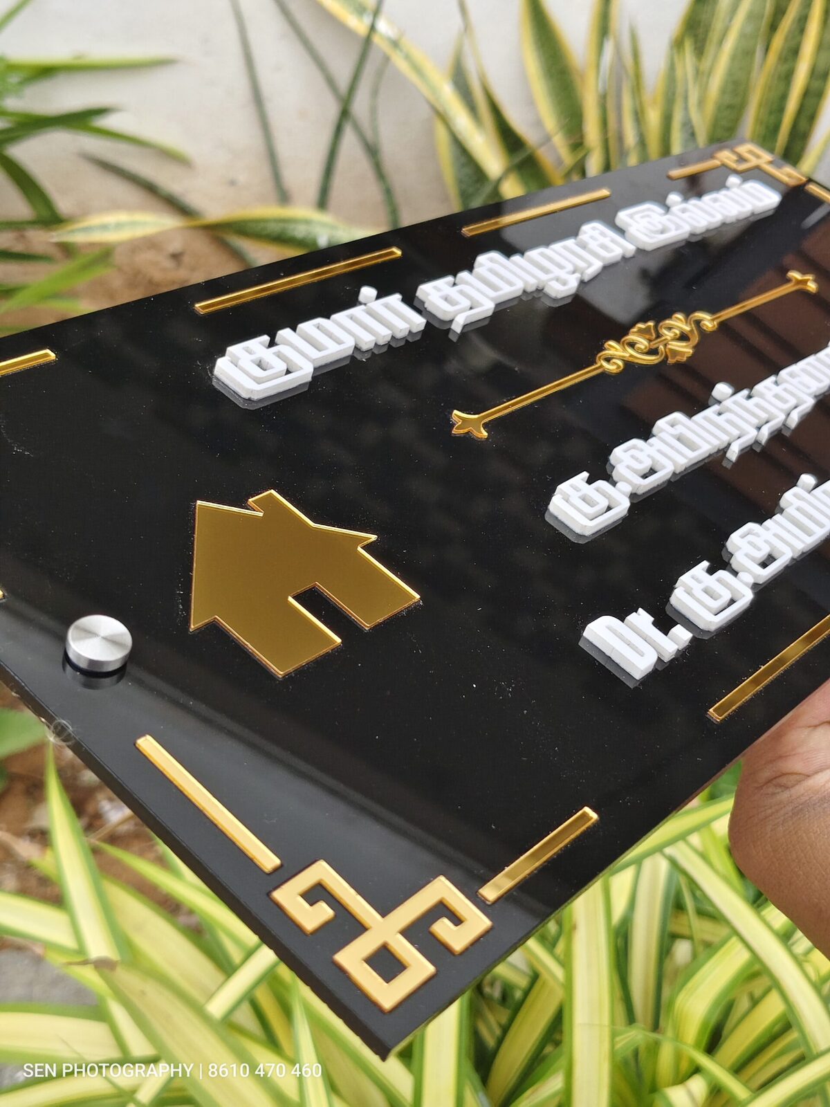 Close view of raised white Tamil lettering on a black name board