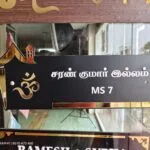 Black acrylic Tamil name board reading Saran Kumar Illam with om symbol