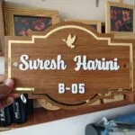Shaped wooden name board with gold border reading Suresh Harini B-05