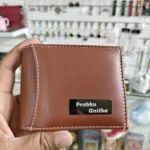 Tan leather wallet with an engraved metal name plate on the front