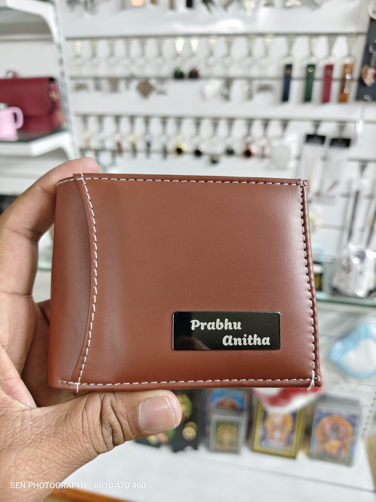 Tan leather wallet with an engraved metal name plate on the front