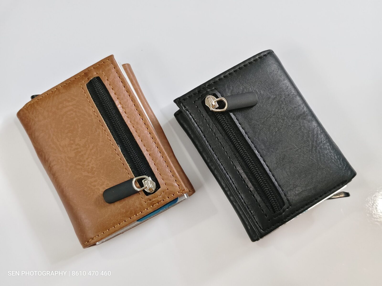 Tan and black slim wallets with metal card holders and strap closure